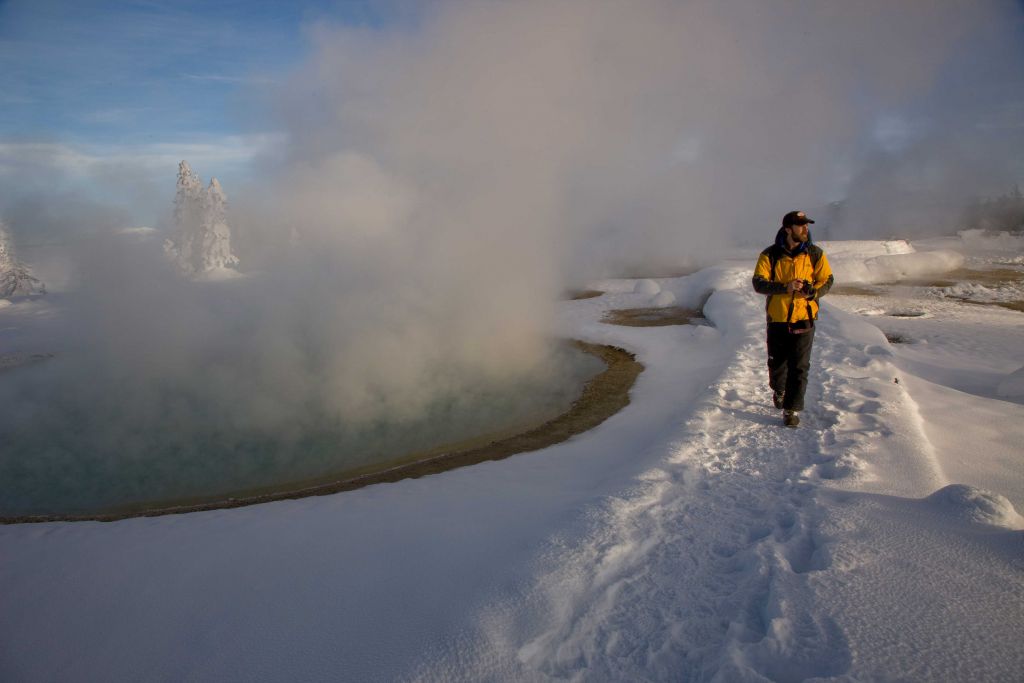 Tourist walking past a geyser in winter
