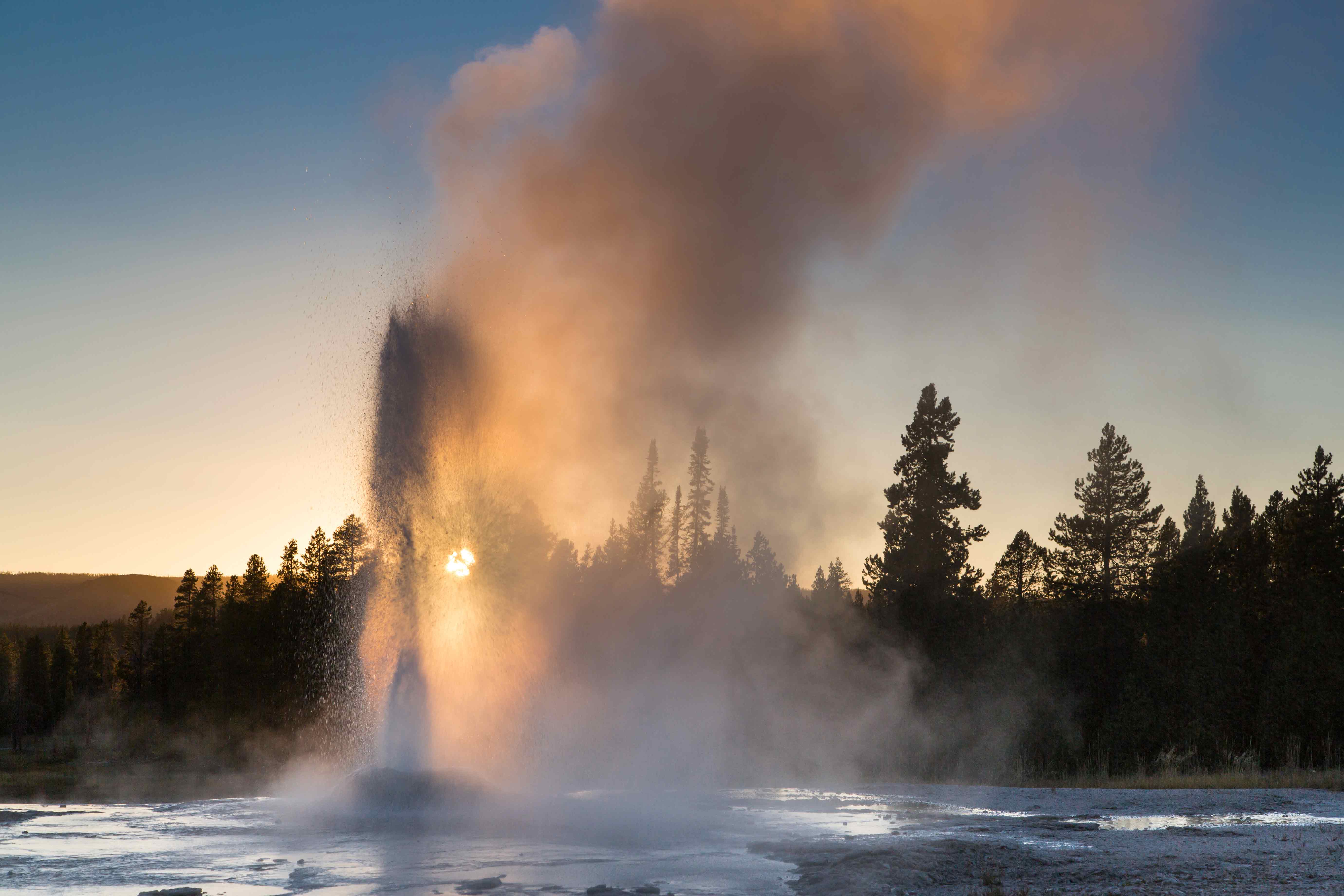 Pink Cone Geyser Erupting with sunset behind