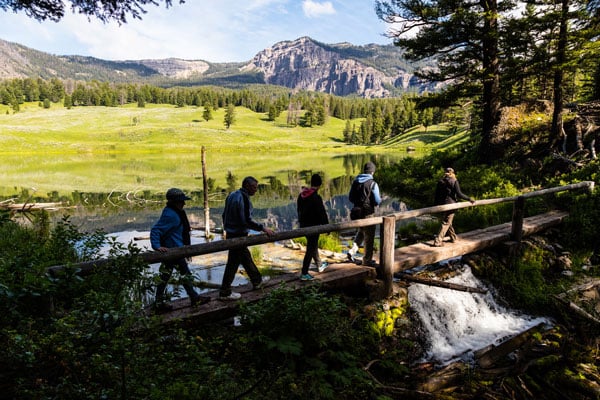 Hikers crossing bridge in front of lake