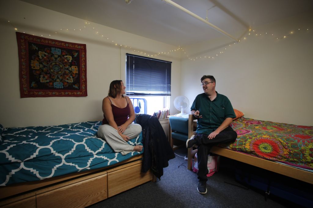 Two employees chat in a dorm room