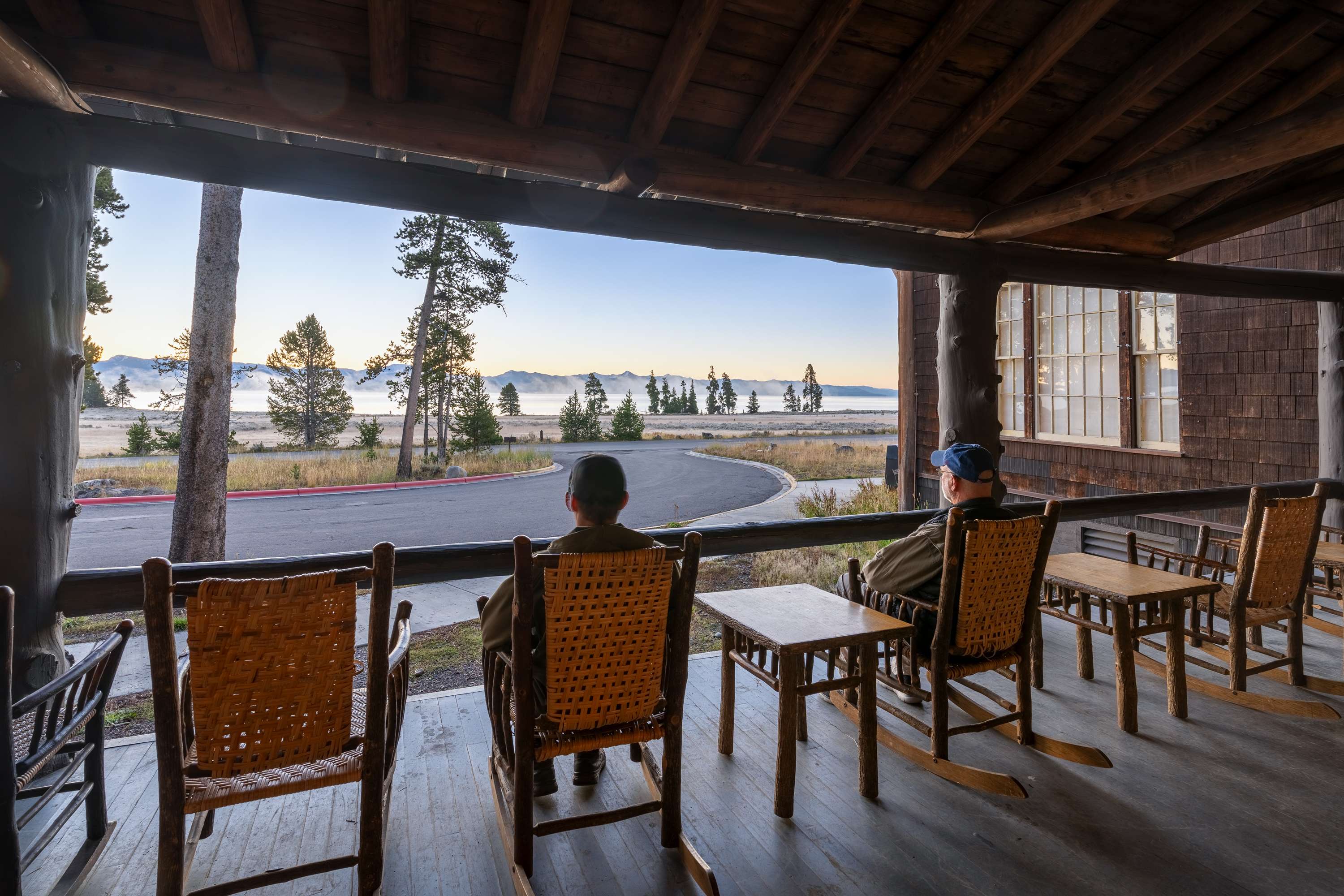 Two people sitting in rocking chairs on the porch of Lake Lodge