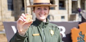 National Park Ranger holding a wooden Junior Ranger Badge