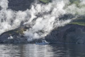 Boat on the water with steam vent in the background