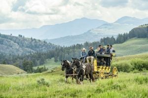 Stagecoache in a valley with mountains in the background