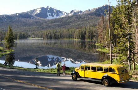 Historic yellow bus in front of a lake