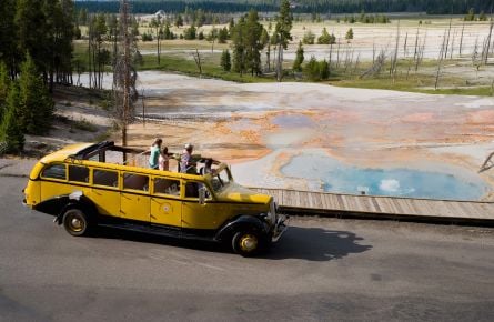 Yellow bus driving past firehole lake