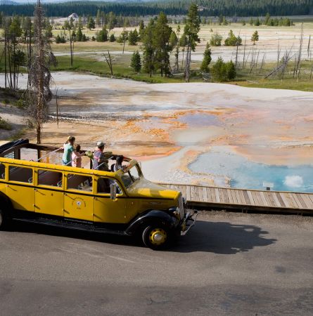 Yellow bus driving past firehole lake