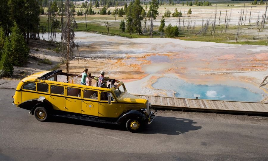 Yellow bus driving past firehole lake