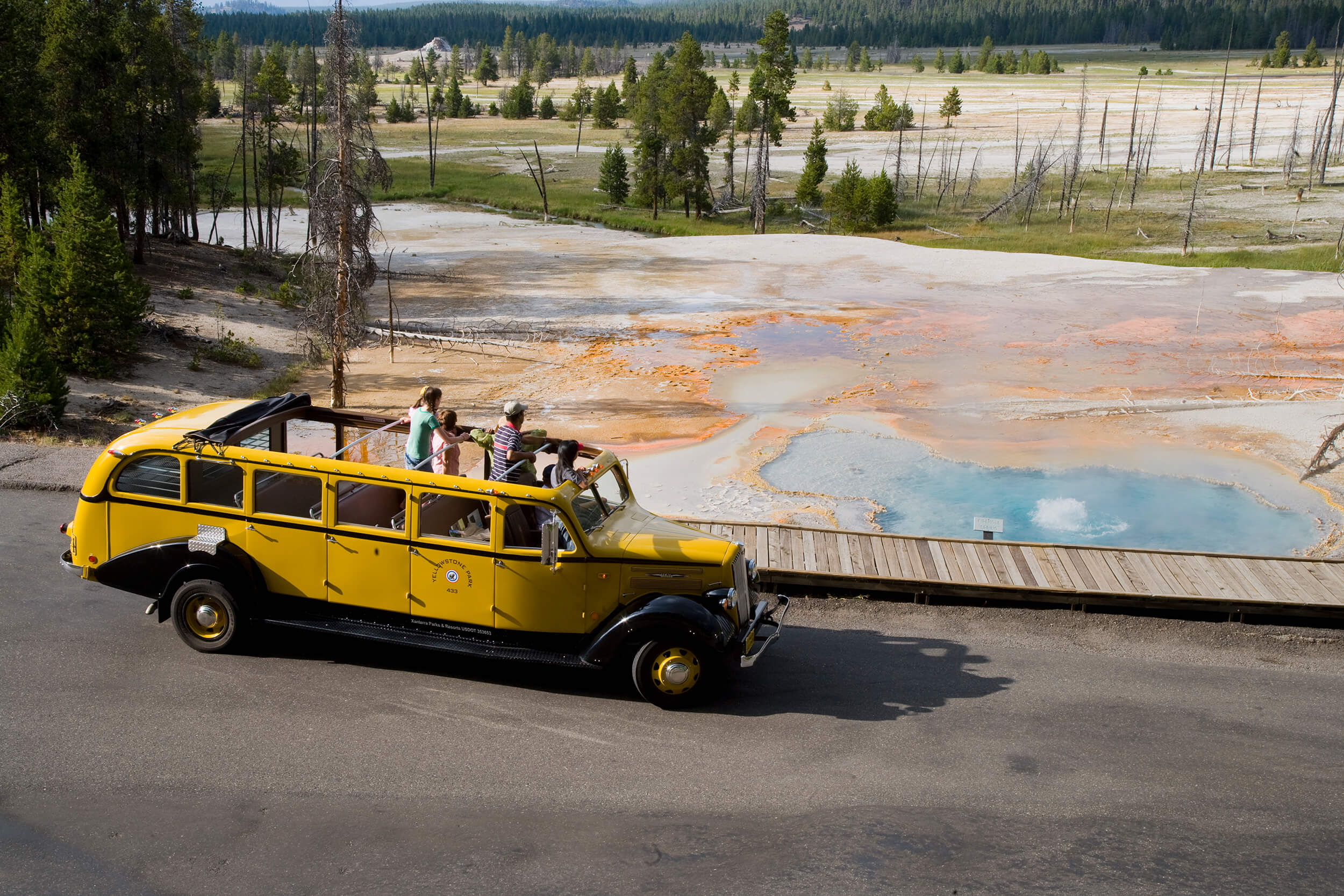 Yellow bus driving past firehole lake