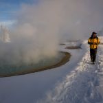 Tourist walking past a geyser in winter