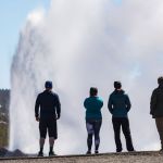 A group of tourists watching a geyser.