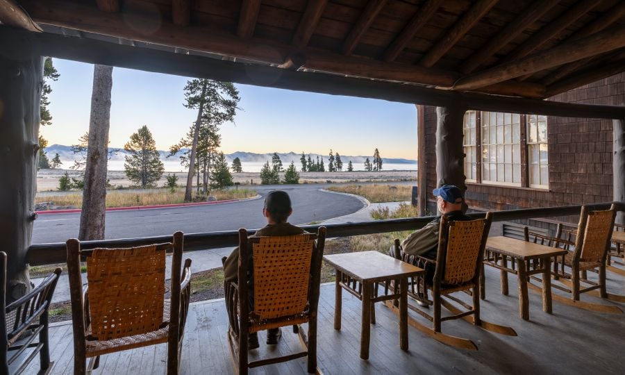 Two people sitting in rocking chairs on the porch of Lake Lodge