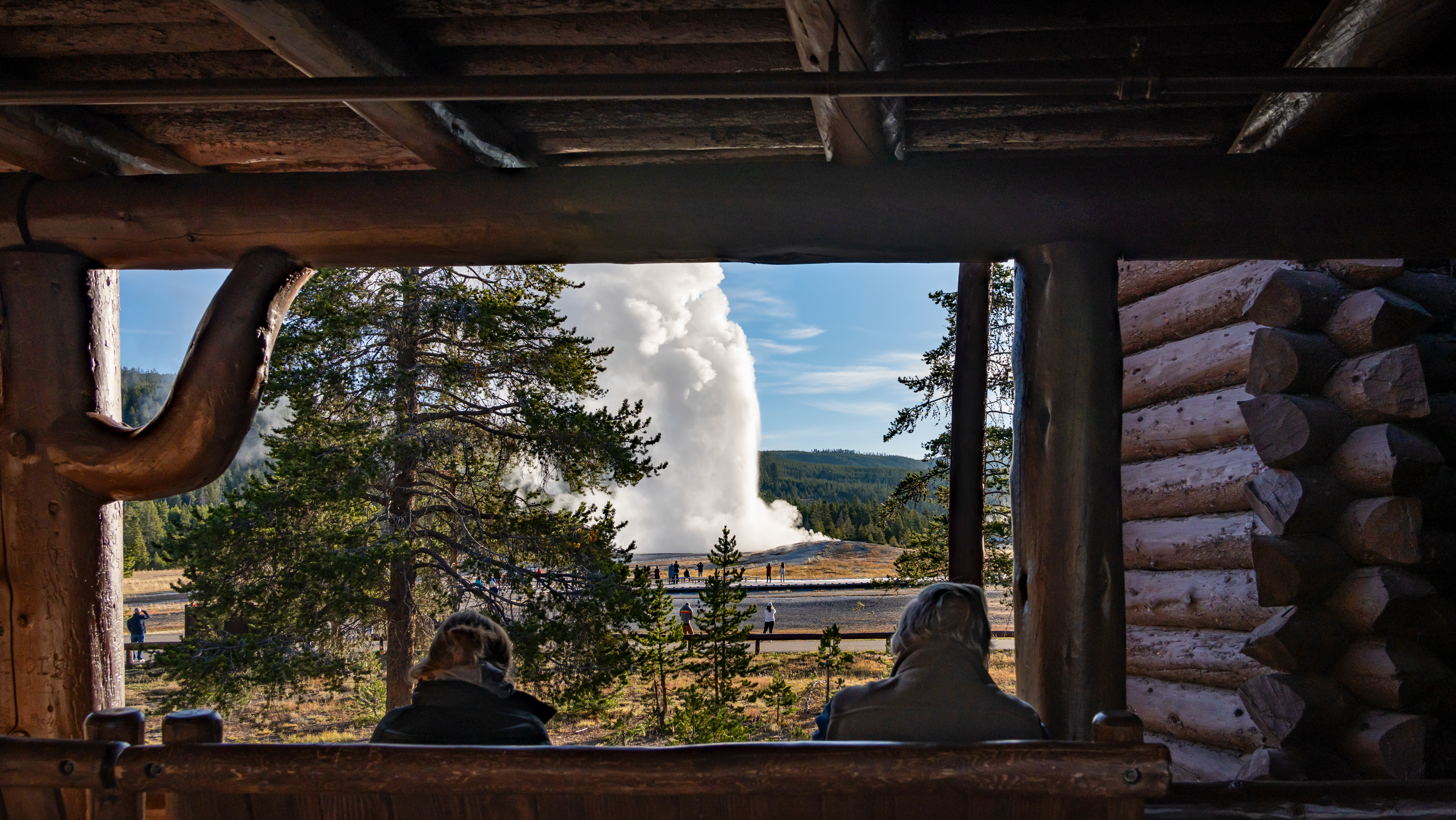 People watching Old Faithful erupt from the breezeway at Old Faithful Inn
