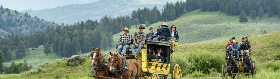 Two stagecoaches in a valley with mountains in the background