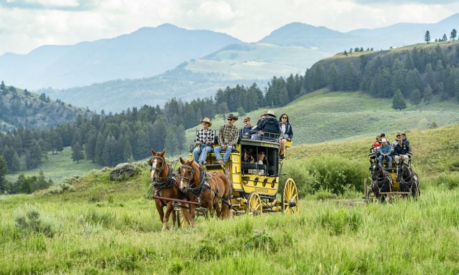 Two stagecoaches in a valley with mountains in the background