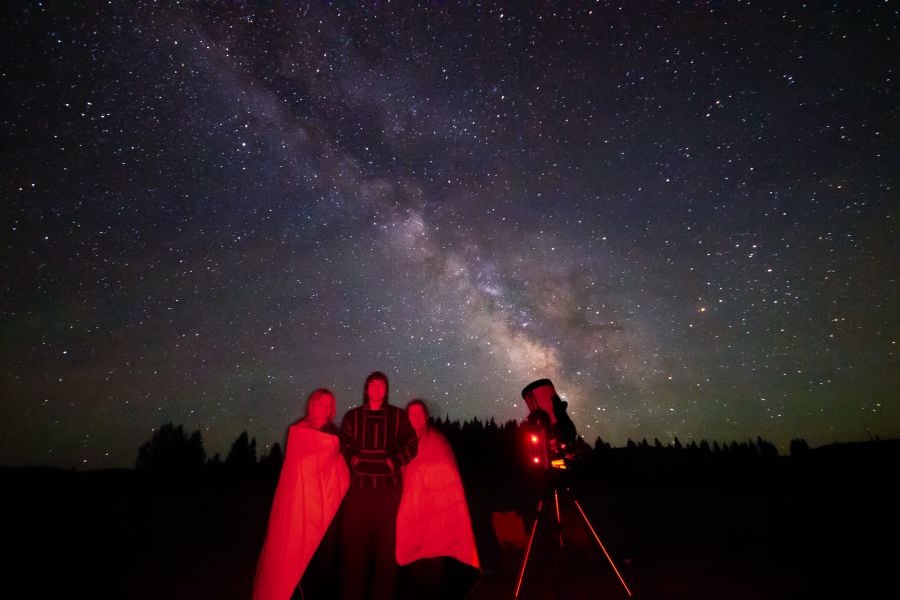 People standing under the Milky Way with telescope